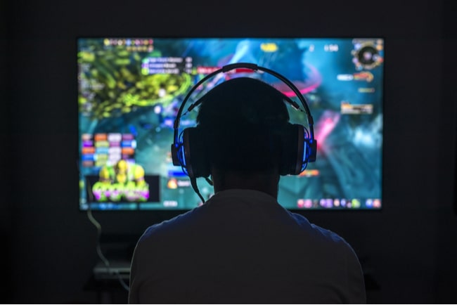 Ung kille framför datorskärm spelar datorspel